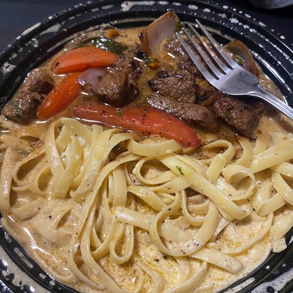 Peruvian Lomo Saltado with steak, red peppers, onions, and fettuccine in a creamy sauce.