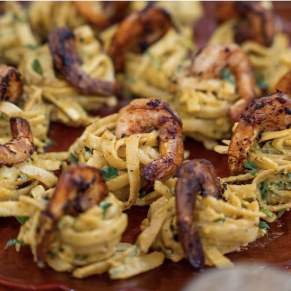 Close-up of Peruvian tallarines verdes with grilled shrimp, garnished with fresh herbs.