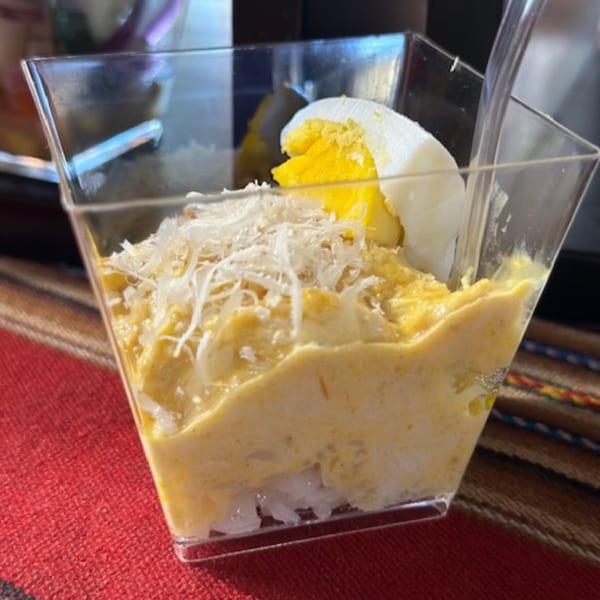 Peruvian Aji de Gallina, a creamy yellow dish topped with shredded cheese and a hard-boiled egg.