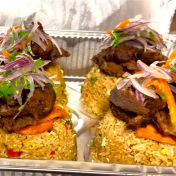 Two servings of Peruvian chaufa rice topped with dark meat, red onions, and cilantro.